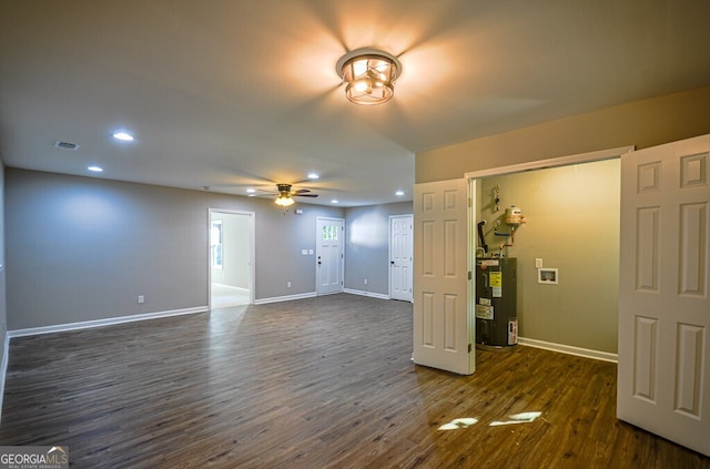 empty room featuring dark hardwood / wood-style floors, ceiling fan, and electric water heater