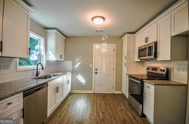 kitchen with dark stone counters, dark hardwood / wood-style floors, sink, white cabinets, and appliances with stainless steel finishes