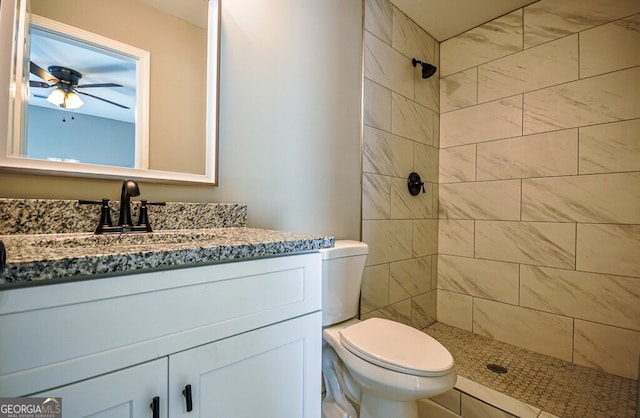 bathroom featuring tiled shower, ceiling fan, vanity, and toilet