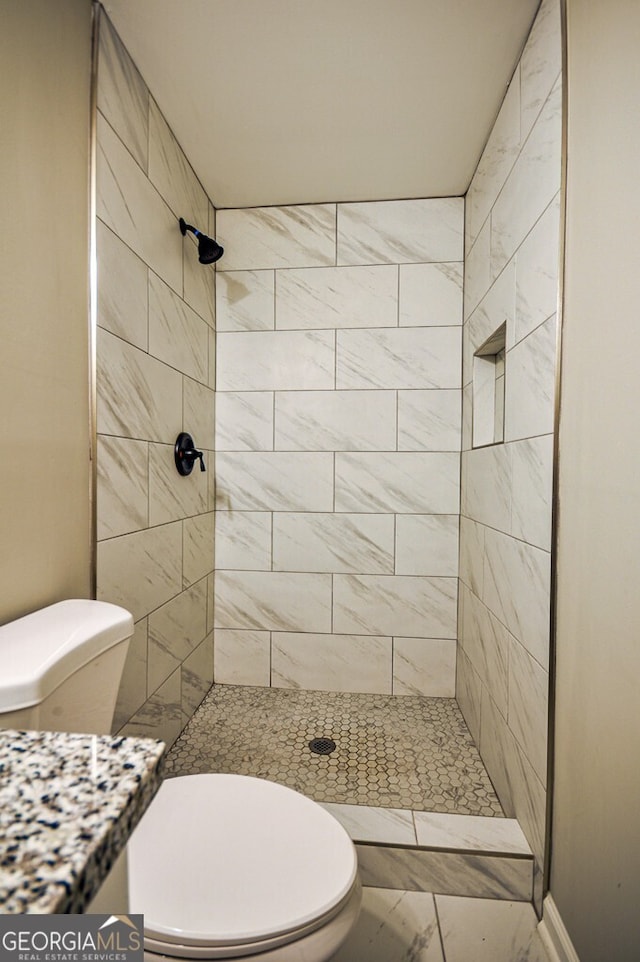 bathroom featuring tiled shower, vanity, and toilet