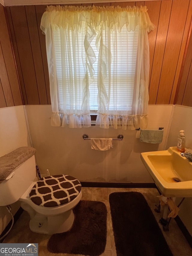 bathroom with wood walls, sink, and toilet