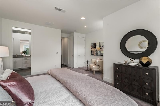 bedroom featuring ensuite bath and light colored carpet