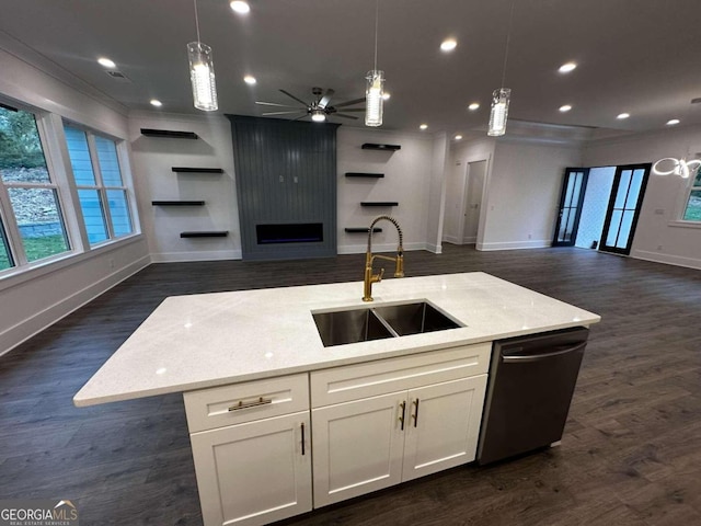 kitchen featuring hanging light fixtures, dishwasher, ceiling fan, a kitchen island with sink, and sink