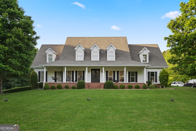 cape cod home with a front yard and a porch