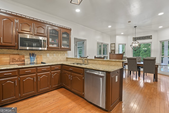 kitchen with appliances with stainless steel finishes, kitchen peninsula, sink, and pendant lighting