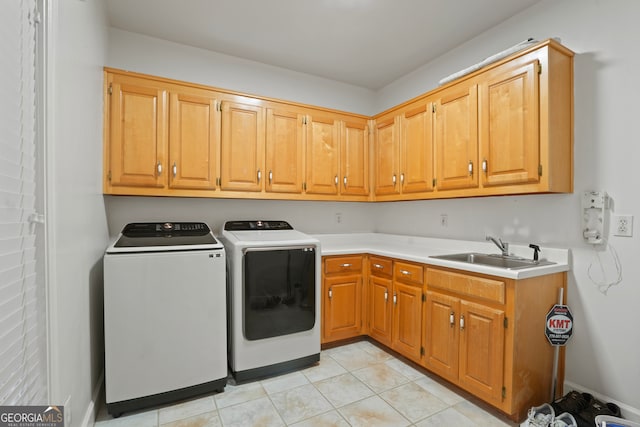 laundry room with light tile patterned floors, sink, washing machine and clothes dryer, and cabinets