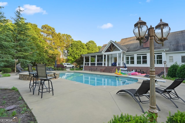 view of swimming pool featuring a sunroom and a patio area