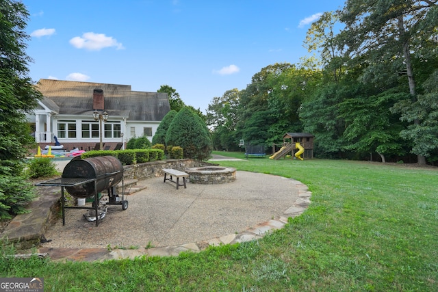 view of yard with a playground, a patio, and an outdoor fire pit