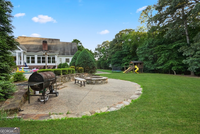 view of yard featuring a playground, a patio, and an outdoor fire pit