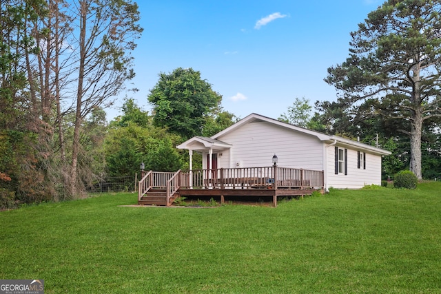 rear view of property featuring a wooden deck and a yard