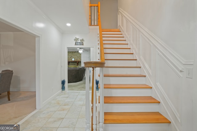 staircase with a fireplace, ornamental molding, and tile patterned floors