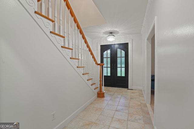 entrance foyer with ornamental molding, light tile patterned floors, and french doors