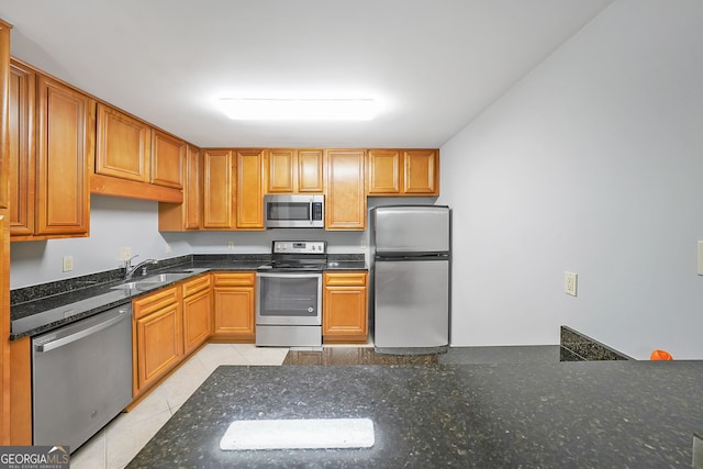 kitchen featuring dark stone counters, appliances with stainless steel finishes, light tile patterned flooring, and sink