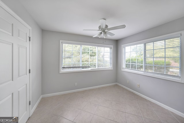 spare room with ceiling fan and light tile patterned floors