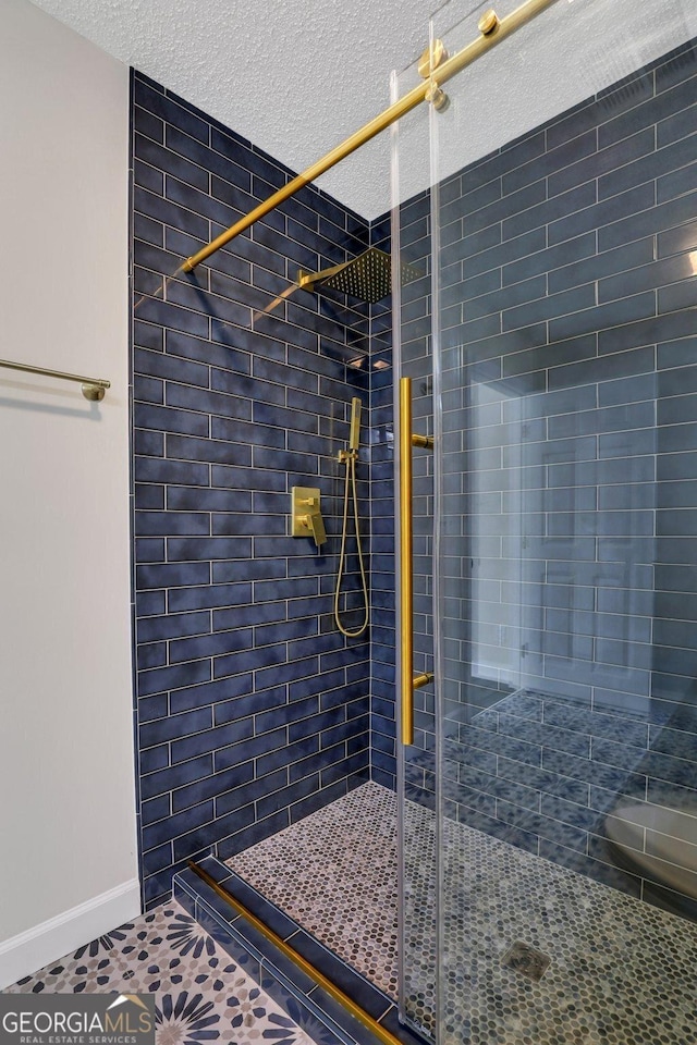 bathroom with tile patterned floors, a tile shower, and a textured ceiling