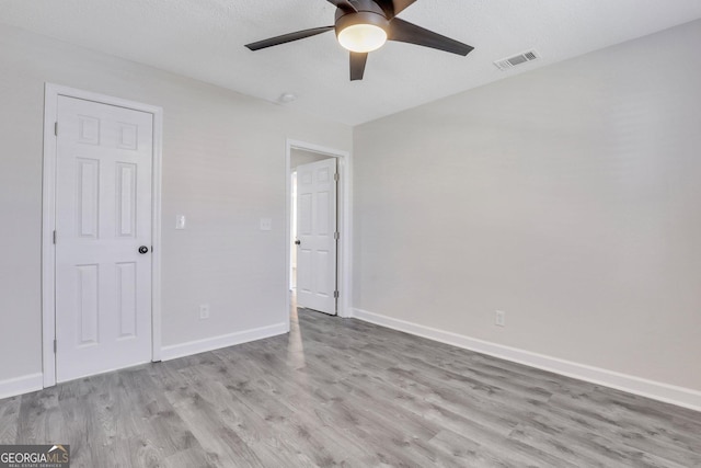 unfurnished room with ceiling fan, light hardwood / wood-style floors, and a textured ceiling