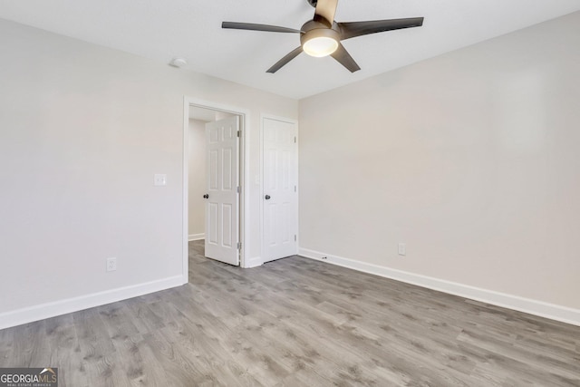 empty room with ceiling fan and light hardwood / wood-style flooring