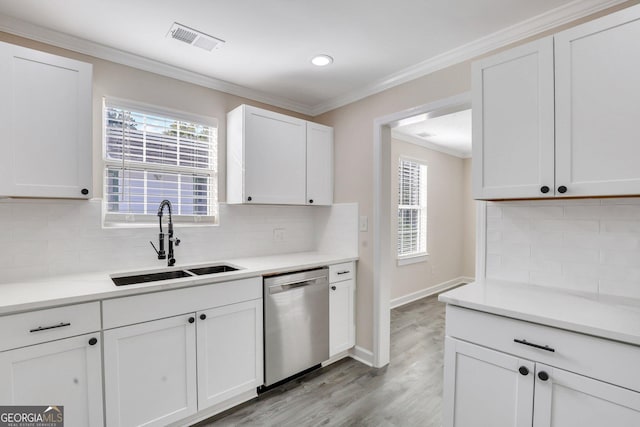 kitchen featuring white cabinets, sink, stainless steel dishwasher, decorative backsplash, and ornamental molding