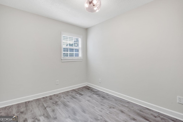 empty room featuring a textured ceiling and light wood-type flooring