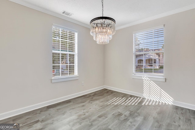 unfurnished room with ornamental molding, a textured ceiling, plenty of natural light, and a notable chandelier