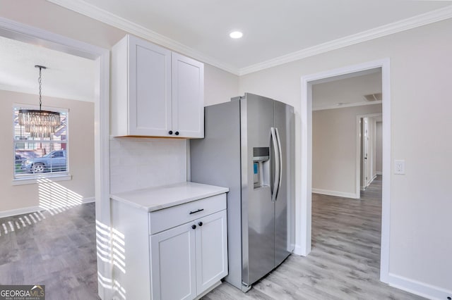 kitchen featuring stainless steel refrigerator with ice dispenser, decorative light fixtures, a notable chandelier, light hardwood / wood-style floors, and white cabinetry