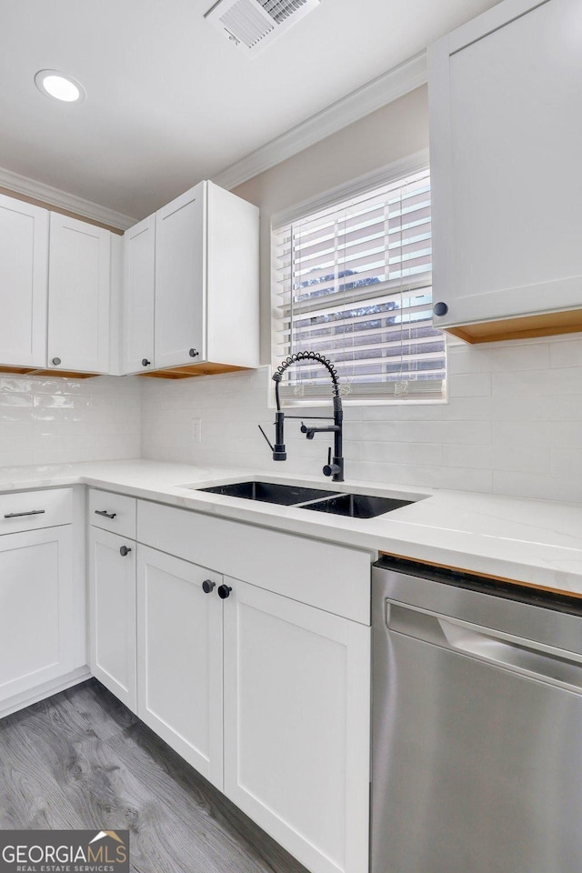 kitchen featuring white cabinetry, sink, stainless steel dishwasher, and hardwood / wood-style flooring