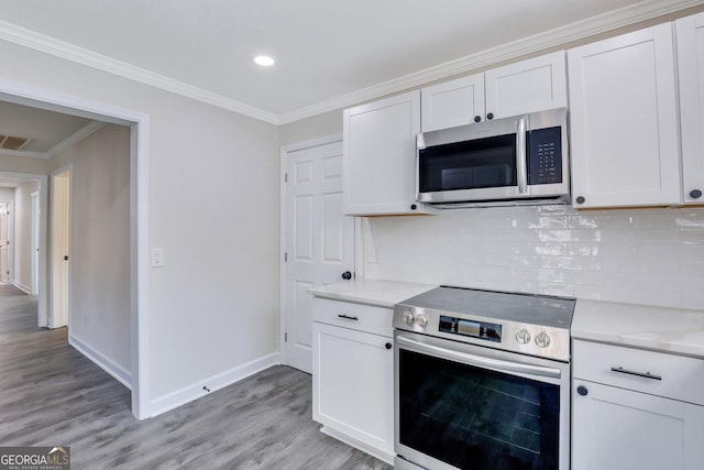 kitchen with white cabinets, crown molding, stainless steel appliances, and tasteful backsplash