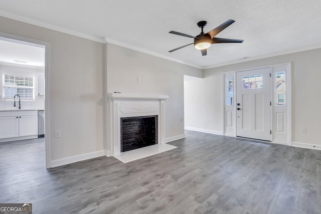 unfurnished living room featuring a fireplace, wood-type flooring, a textured ceiling, and ornamental molding