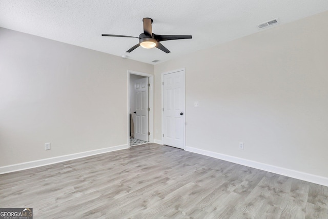 empty room with ceiling fan, light hardwood / wood-style flooring, and a textured ceiling