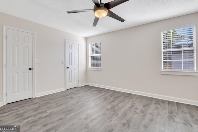 unfurnished room with ceiling fan, light hardwood / wood-style flooring, and a textured ceiling