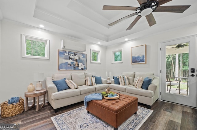 living room with a wall mounted air conditioner, dark hardwood / wood-style flooring, a tray ceiling, and a healthy amount of sunlight