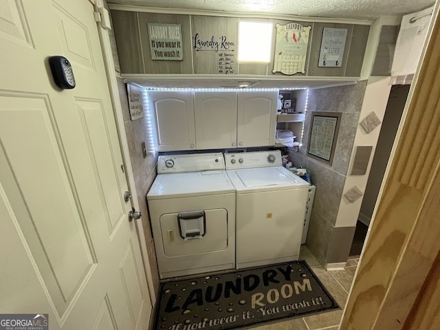 laundry area featuring a textured ceiling, independent washer and dryer, tile patterned floors, and cabinets