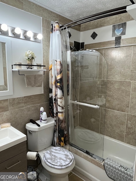 full bathroom with tile walls, a textured ceiling, shower / bathtub combination with curtain, vanity, and toilet