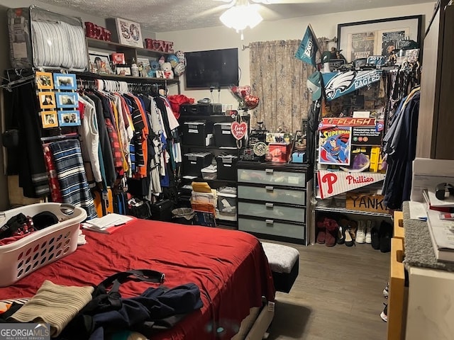 bedroom featuring a textured ceiling, wood-type flooring, and ceiling fan