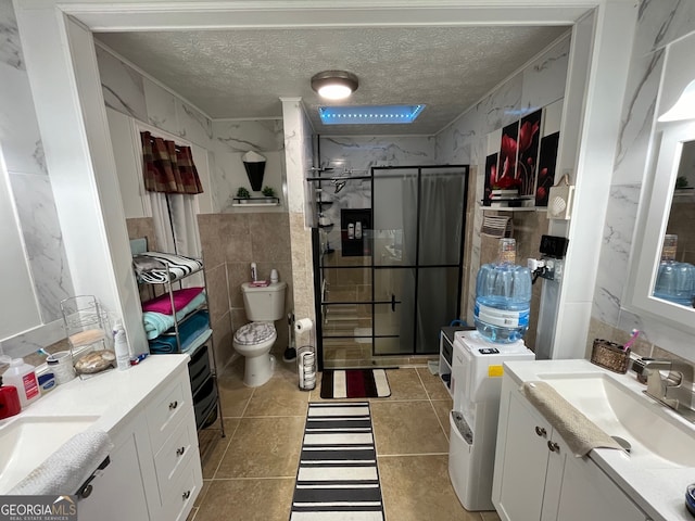 bathroom with tile patterned flooring, a shower with door, vanity, and toilet