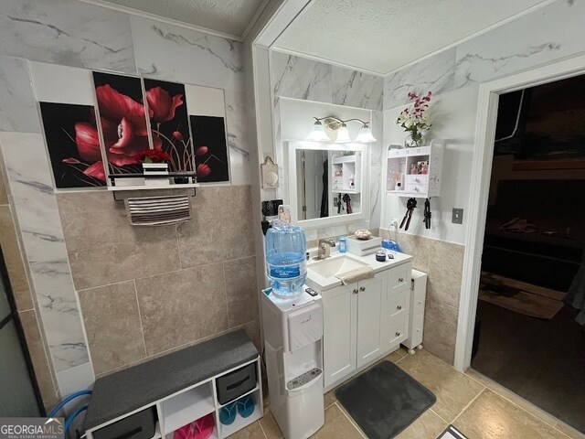 bathroom featuring a textured ceiling, tile walls, tile patterned flooring, and vanity