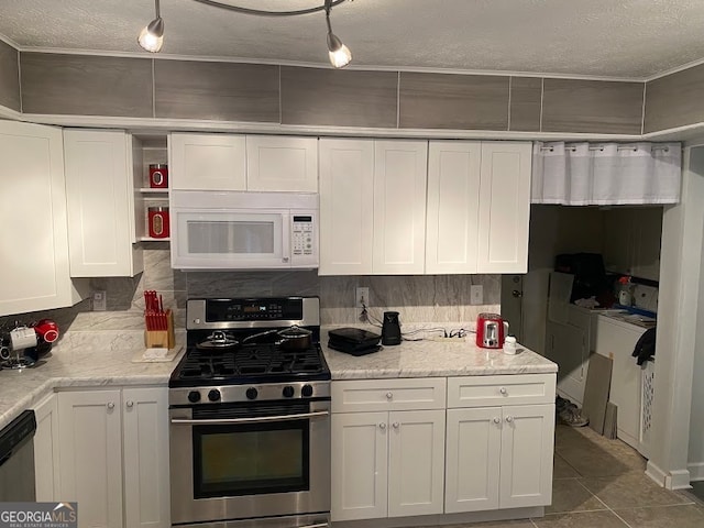 kitchen with appliances with stainless steel finishes, white cabinetry, independent washer and dryer, backsplash, and tile patterned floors