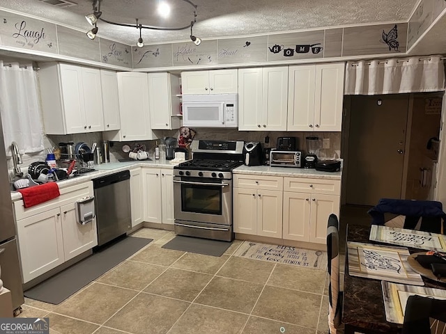 kitchen featuring white cabinets, a textured ceiling, stainless steel appliances, and tile patterned flooring