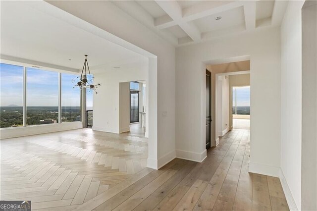 interior space featuring coffered ceiling, beamed ceiling, a notable chandelier, and light hardwood / wood-style flooring