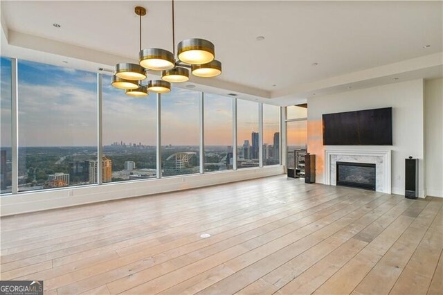 unfurnished living room with a notable chandelier, light wood-type flooring, and a fireplace