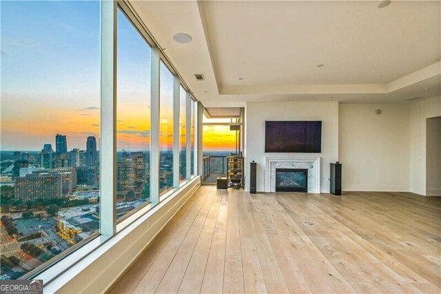 living room featuring light hardwood / wood-style floors, a premium fireplace, and a raised ceiling