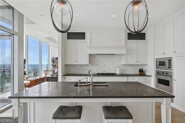 kitchen with white cabinets, an island with sink, appliances with stainless steel finishes, and sink