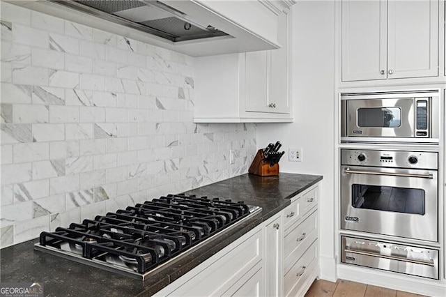 kitchen featuring decorative backsplash, white cabinetry, stainless steel appliances, light hardwood / wood-style flooring, and premium range hood