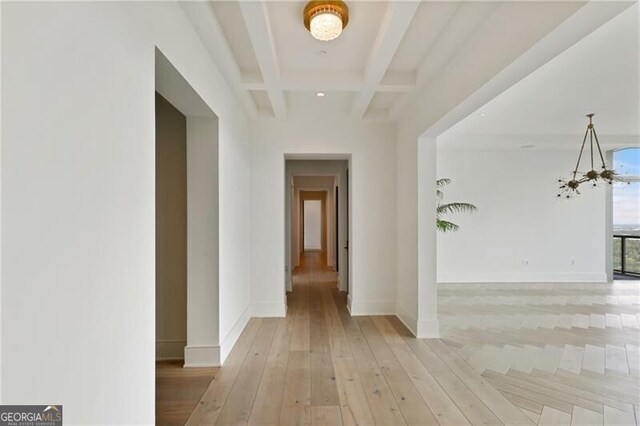 hallway featuring coffered ceiling, beam ceiling, light hardwood / wood-style flooring, and a chandelier