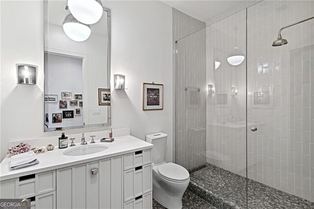 bathroom with a tile shower, vanity, and toilet