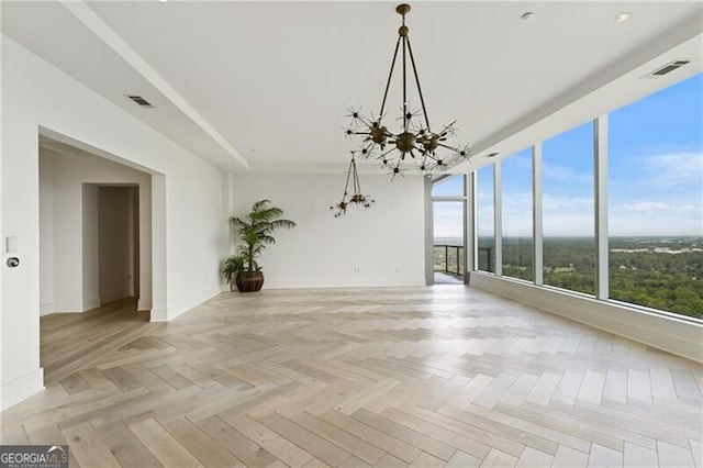 spare room featuring an inviting chandelier and light parquet floors