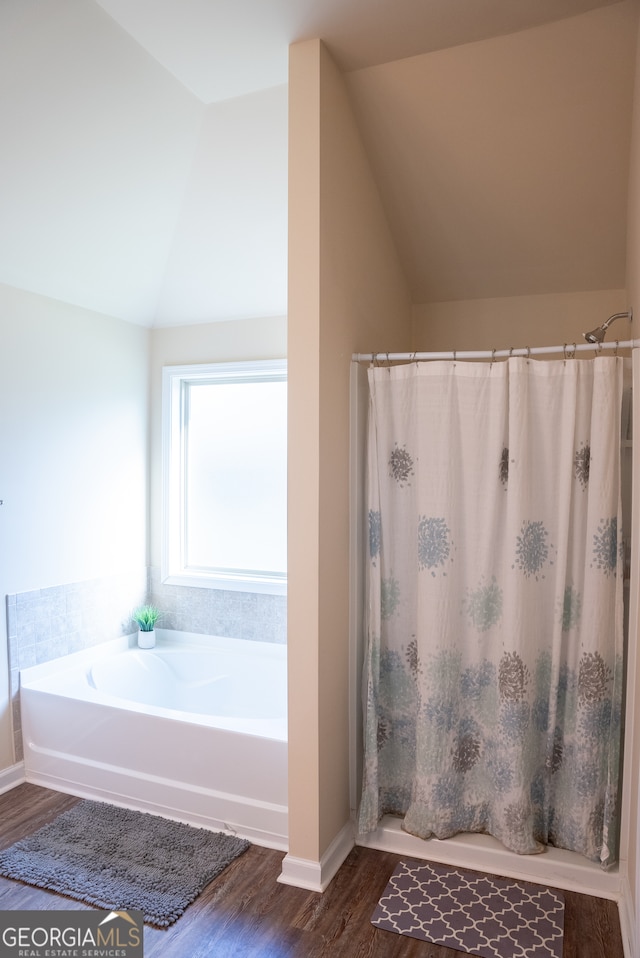 bathroom featuring lofted ceiling, hardwood / wood-style floors, and plus walk in shower