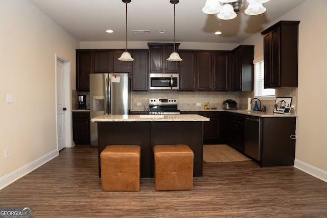 kitchen featuring dark wood-type flooring, a kitchen island, pendant lighting, stainless steel appliances, and sink