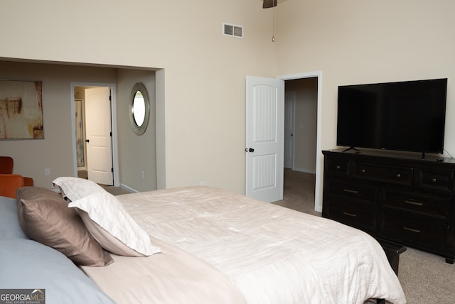 bedroom with a high ceiling and light colored carpet