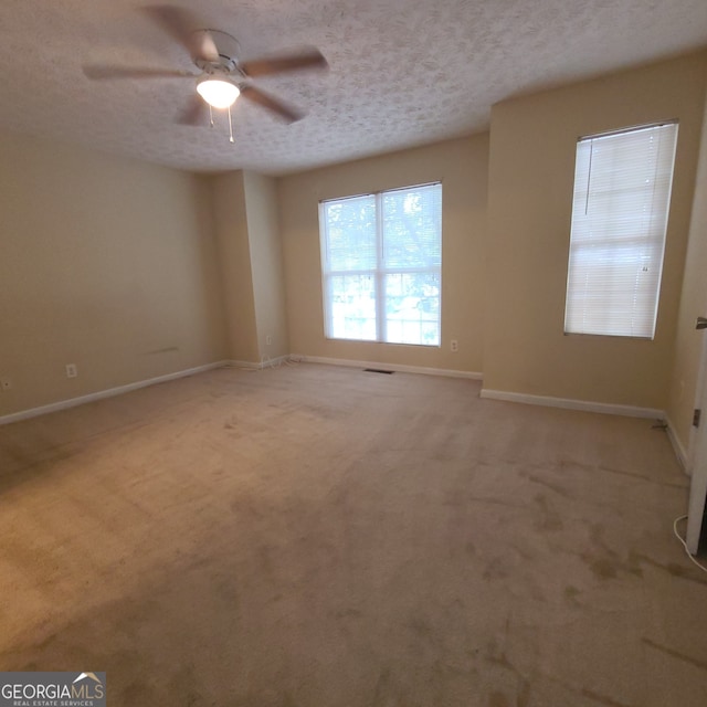 carpeted empty room with ceiling fan and a textured ceiling